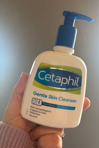 a hand holding a bottle of cetaphil skin cleanser