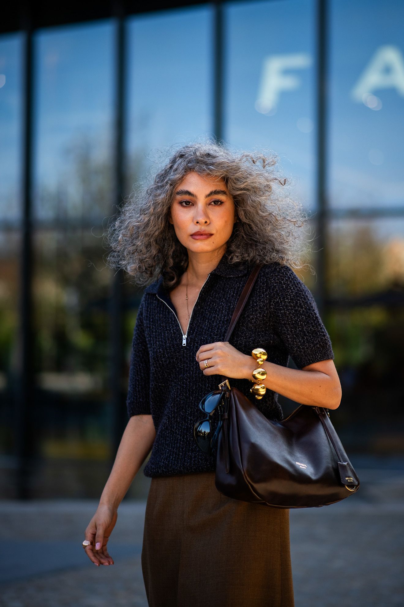 a woman with curly gray hair in a black shirt and brown skirt
