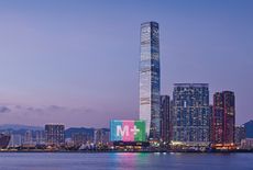 View of illuminated facade of M+ museum, amid the Hong Kong skyline