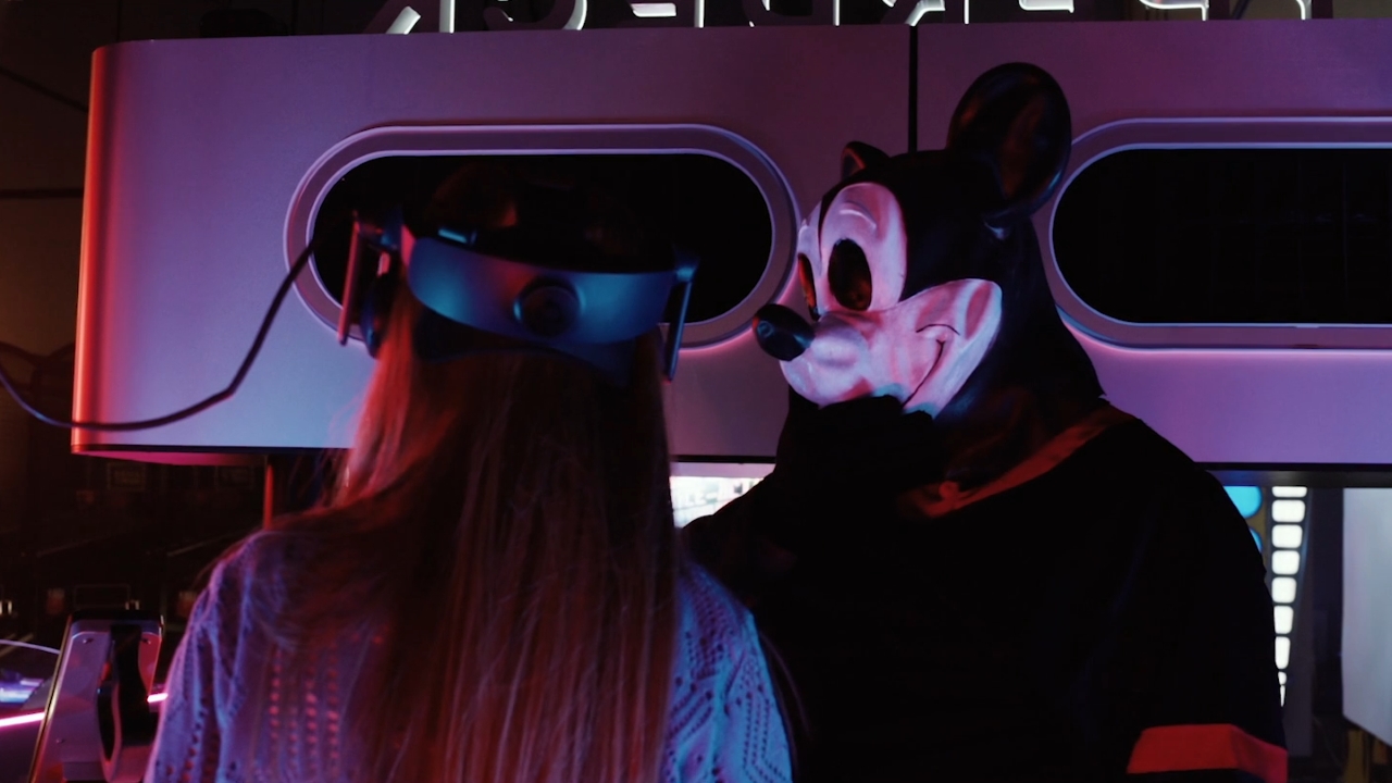 Mickey Fare Kapanı'nda VR oynayan kıza bakıyor