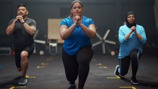 Three people perform the lunge exercise in a gym