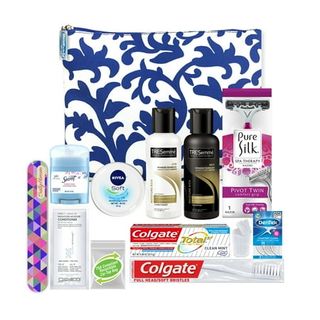 A blue and white paisley bag behind a collection of small travel sized toiletries