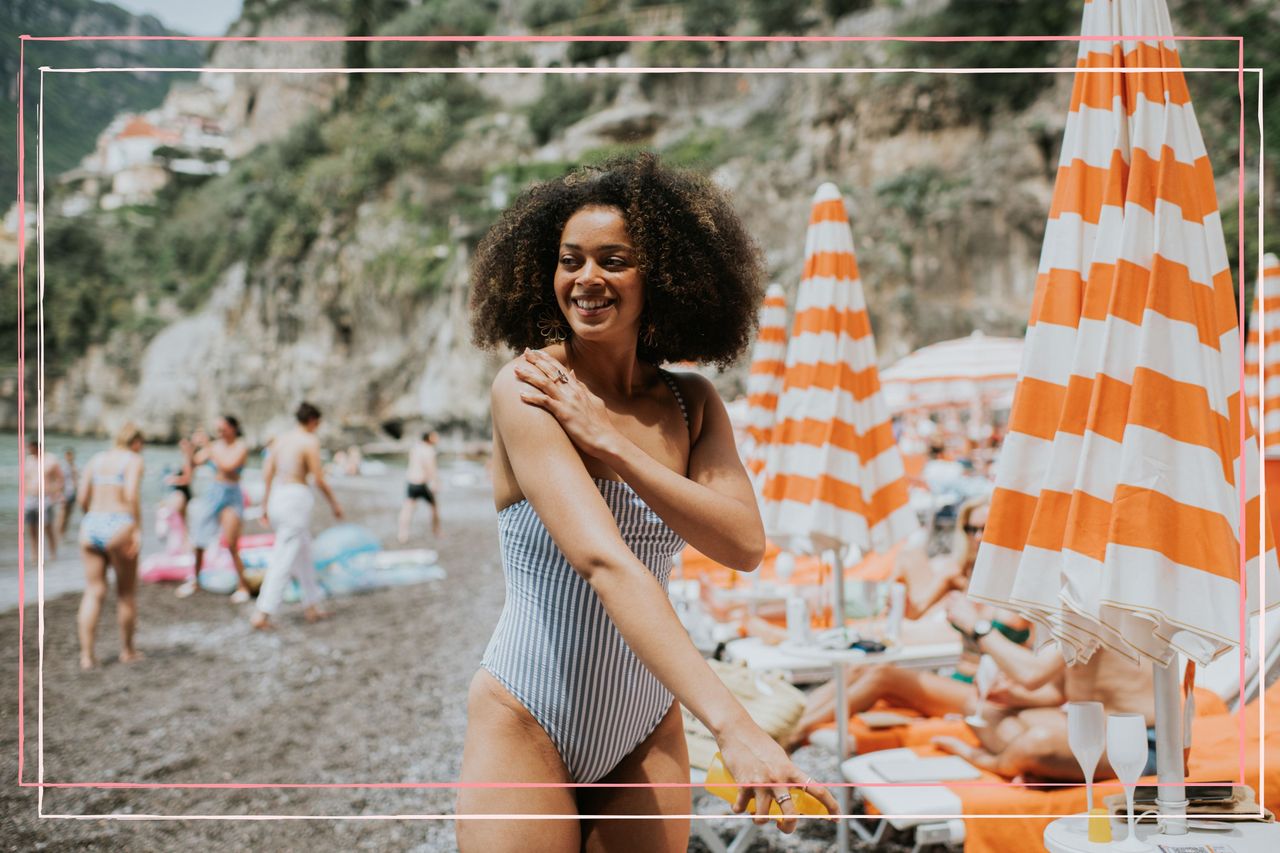 A woman applying sun cream on a beach whilst thinking how often should you apply sun cream