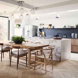 Open-plan kitchen diner with dining table, island and parquet flooring