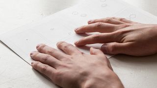 Hands reading the braille comic book