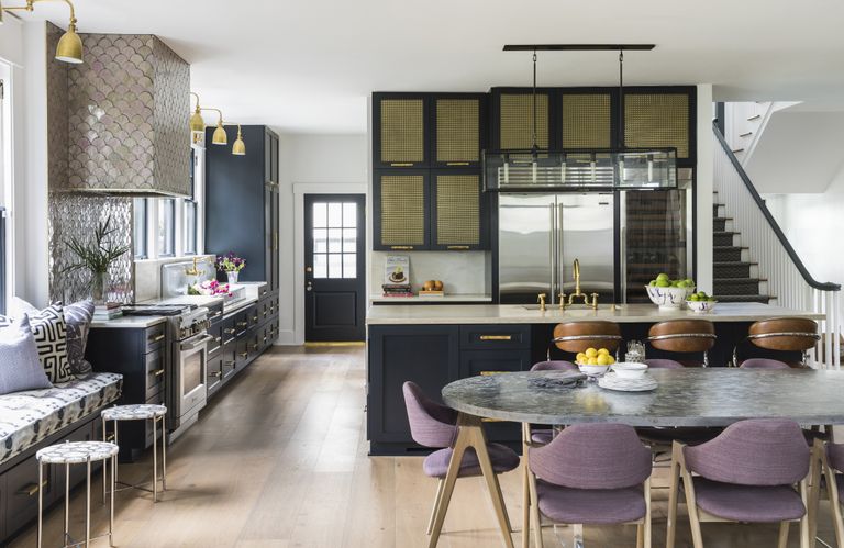 黑色厨房，金色灯光，大理石餐桌和紫色椅子。