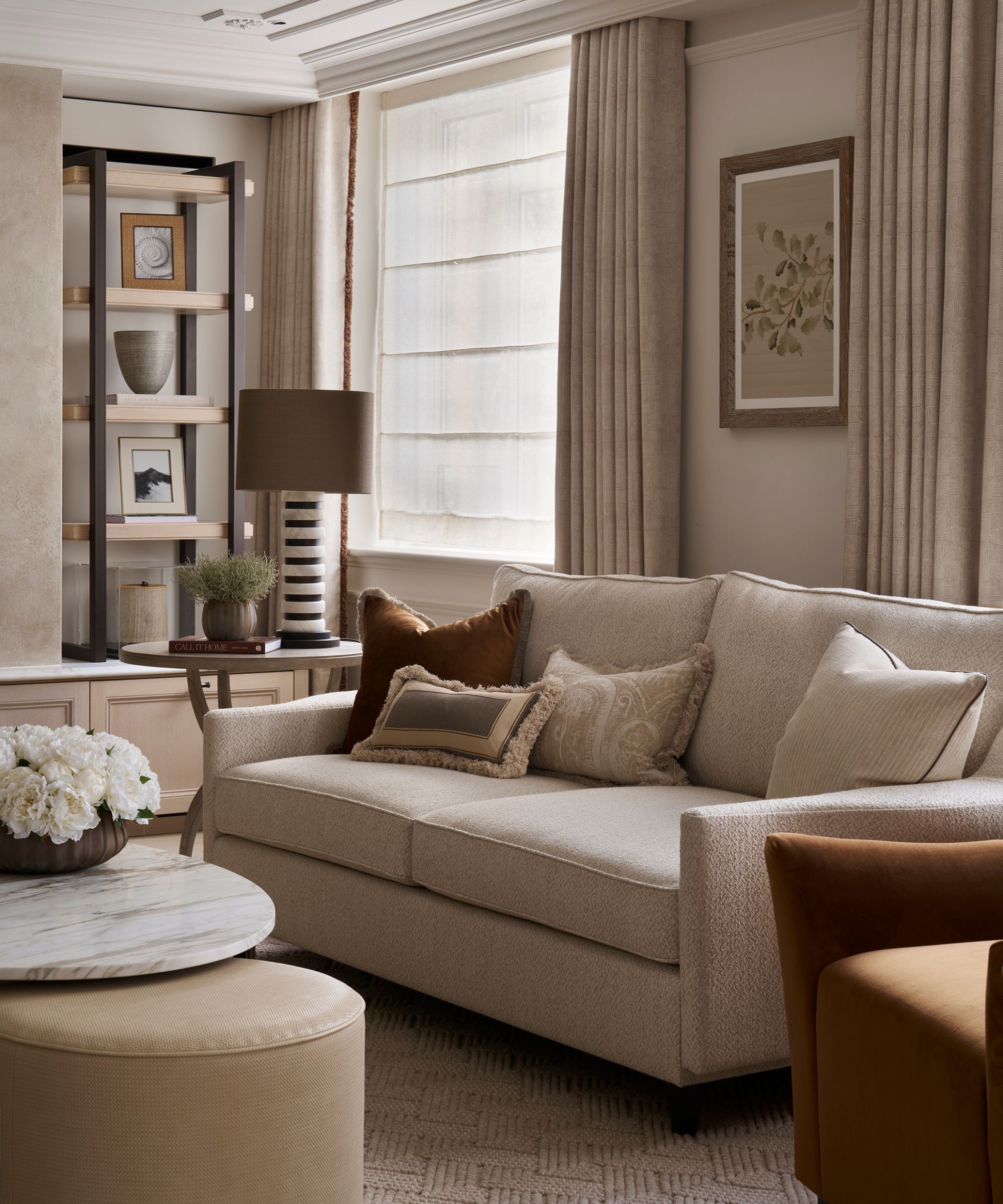 a neutral quiet luxury living room with a neutral sofa, custom shelving, a marble coffee table and a textured rug
