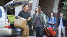 A dad and his daughter unpack the car as they move her into a college dorm.