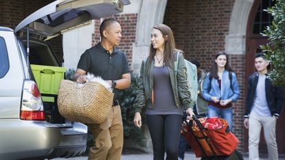 A dad and his daughter unpack the car as they move her into a college dorm.