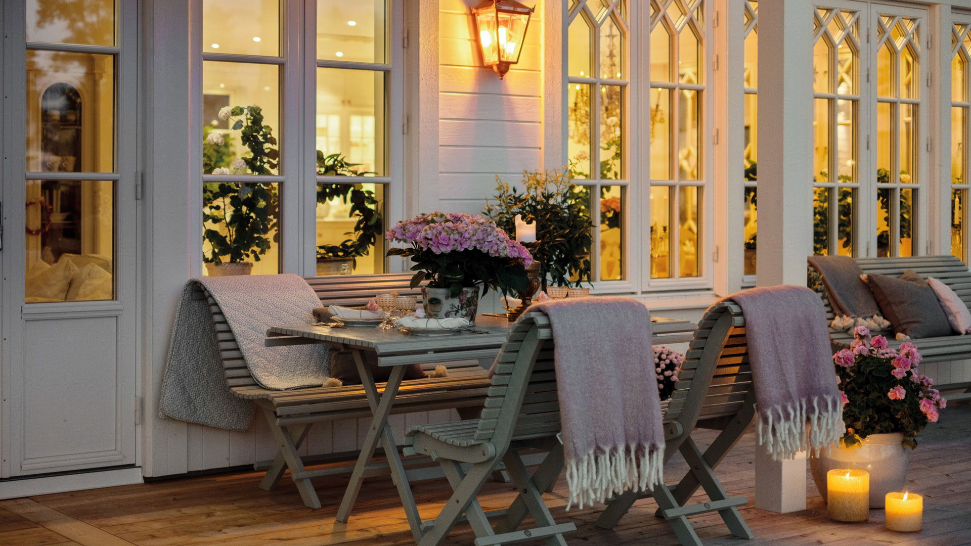 decking with wall lights and table and chairs with throws