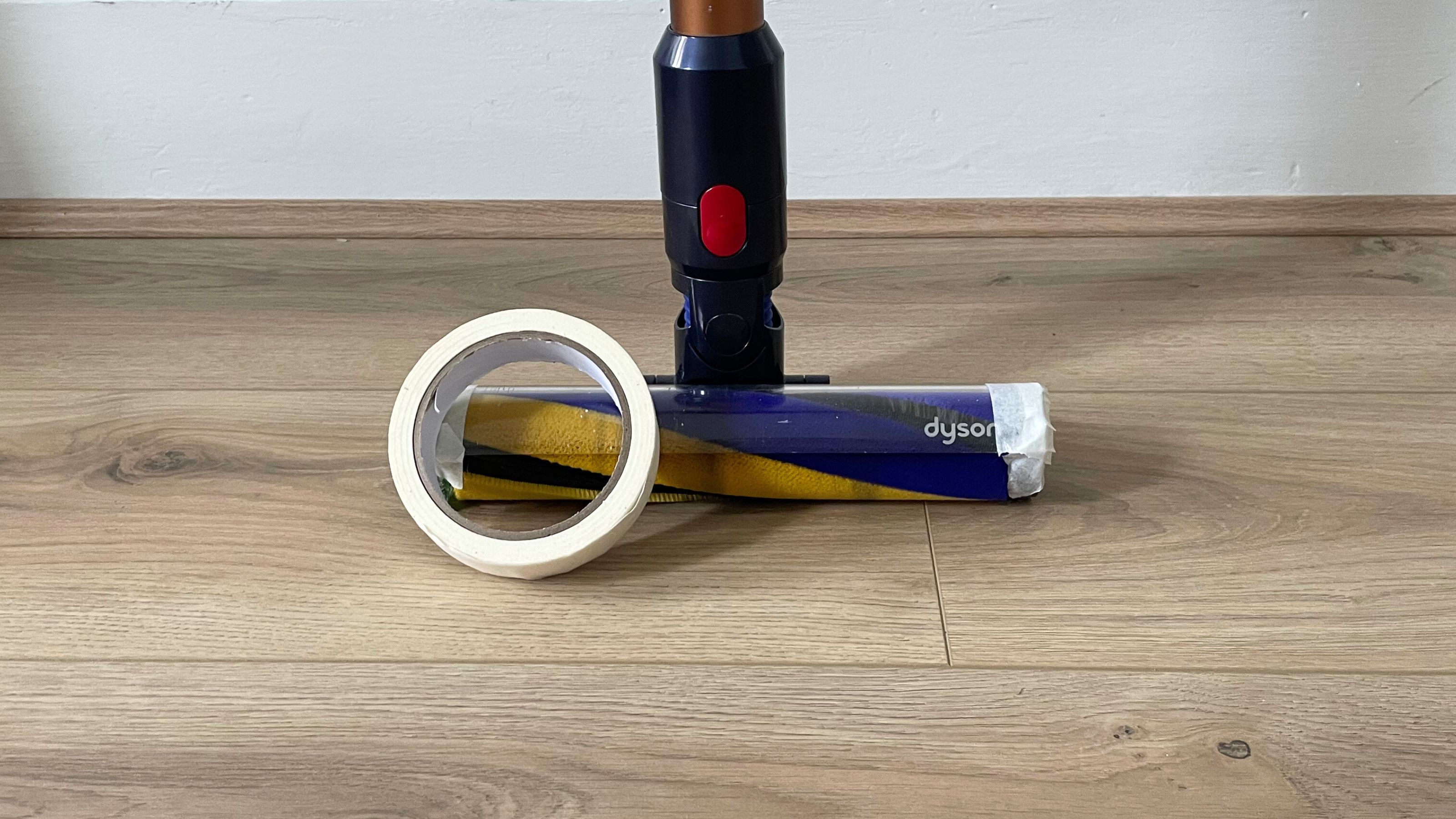 Dyson Gen5detect on wood-effect flooring with a roll of masking tape in front of it