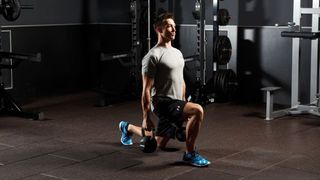 Man performs lunge holding kettlebells