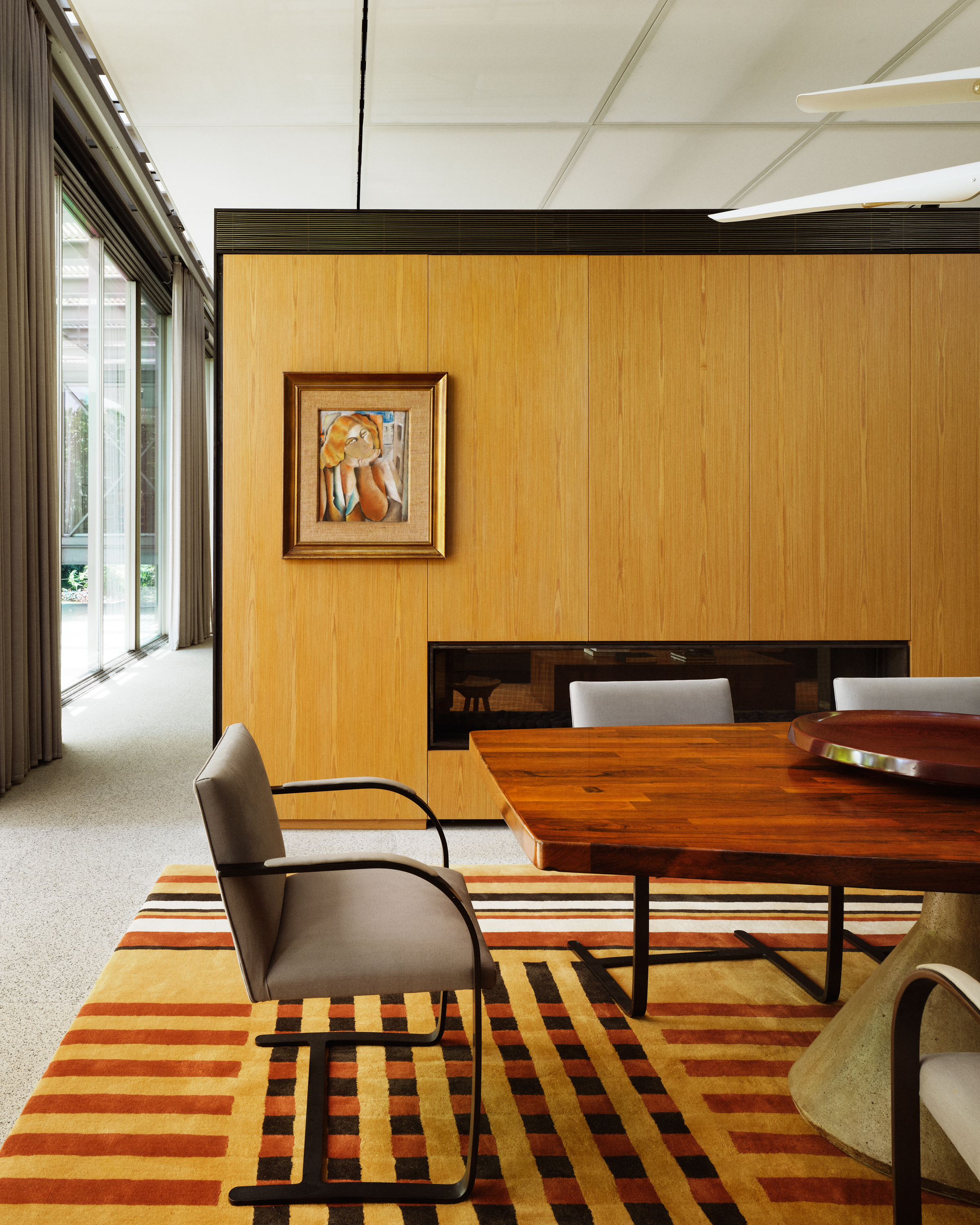 An image of a plaid-striped rug placed within a midcentury home.