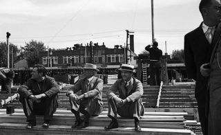 Black and white photo of men wearing suits sitting on steps