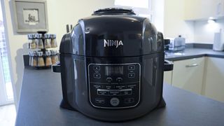 En svart airfryer av typen Ninja Foodi Multi-Cooker står på en mörk köksbänk.