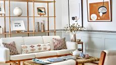 A mid-century style living room with a cream sofa, and an open wooden shelving unit behind it.