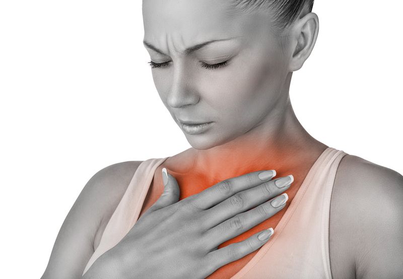 A woman holds her chest in pain.