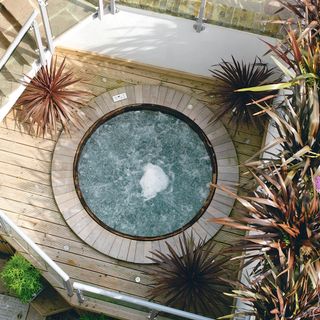 A circular hot tub recessed into a paved outdoor area