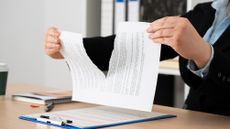 A lawyer tears up a contract, only her hands showing.