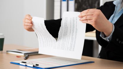 A lawyer tears up a contract, only her hands showing.