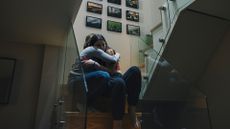 mother and daughter sat on the stairs hugging