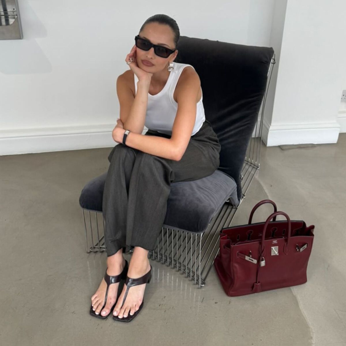 A photo of Pia Mance wearing Bottega Veneta's extended thong sandals with gay pants and a white tank top.