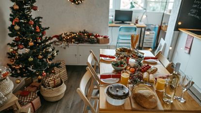 We wanted to know how to host Christmas in a small space like this cozy kitchen with a christmas tree and tiny table set for dinner and our 7 expert tips delivered
