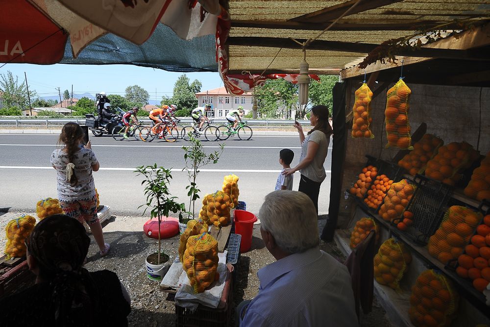 Spectators watch the race from a roadside fruit stand.