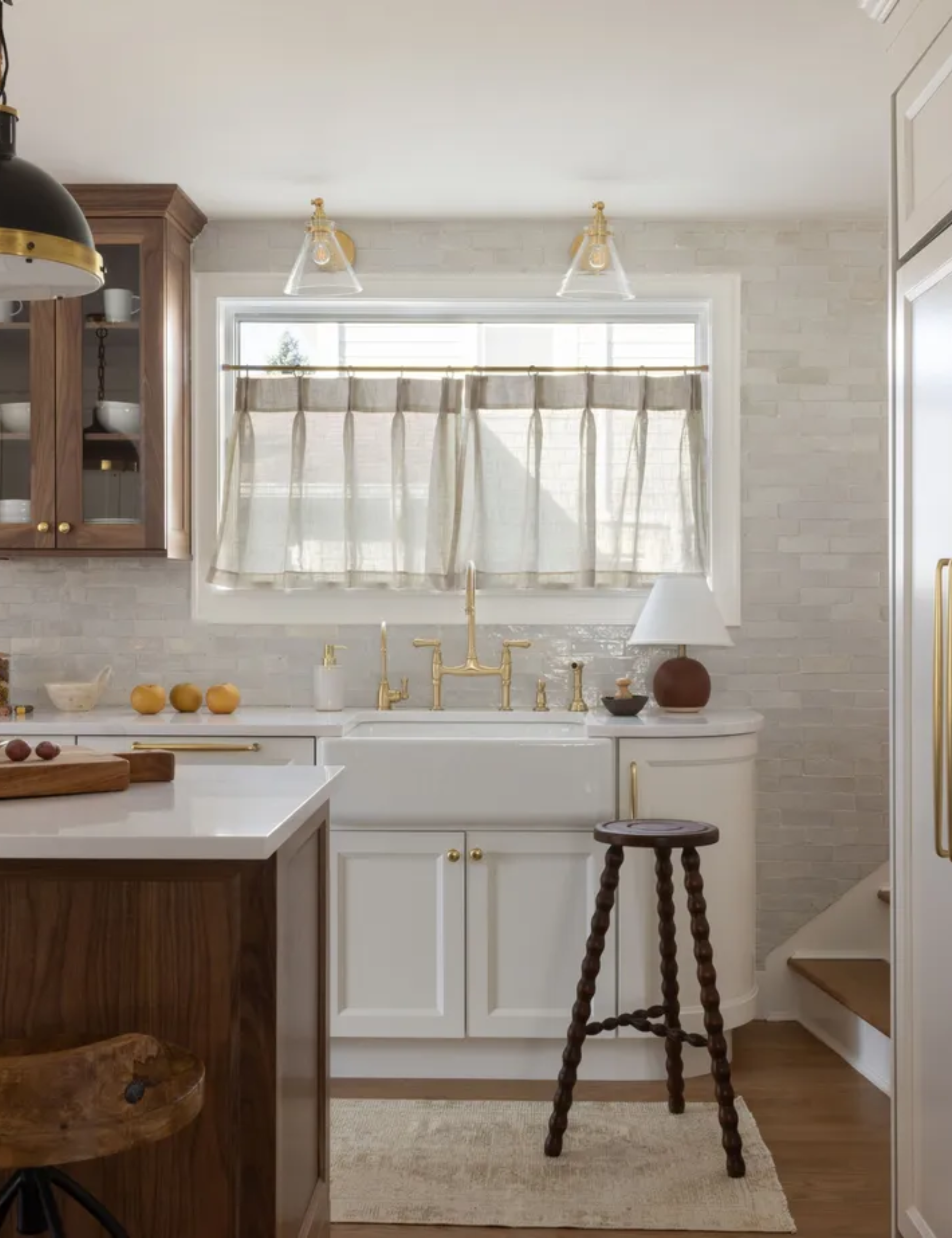 Neutral kitchen with cafe curtains a wood island, gold hardware and ambient lighting. Interior by Danielle Rose Designs
