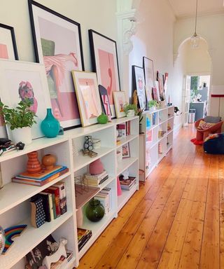 A entryway with shelves filled with colorful decor and wall art, white walls, and wooden flooring
