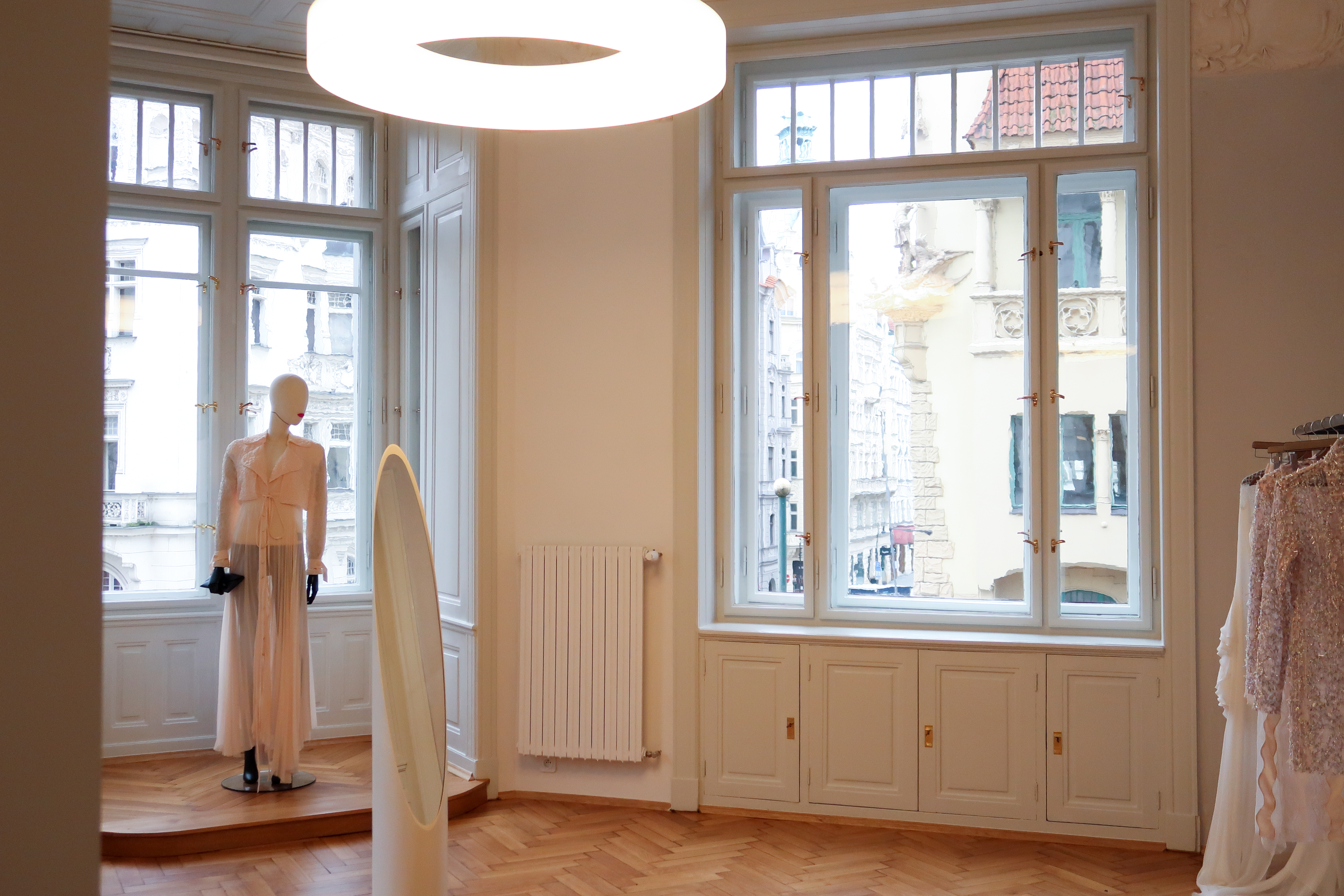 A fashion atelier tucked inside a historical palace boasts wooden floors, minimalist design, circular, doughnut-shaped neon lights, and haute-couture creations.
