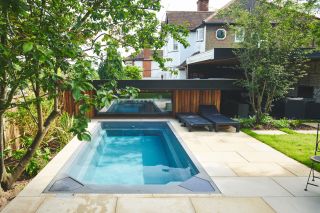 small swimming pool with garden rooms at bottom of garden