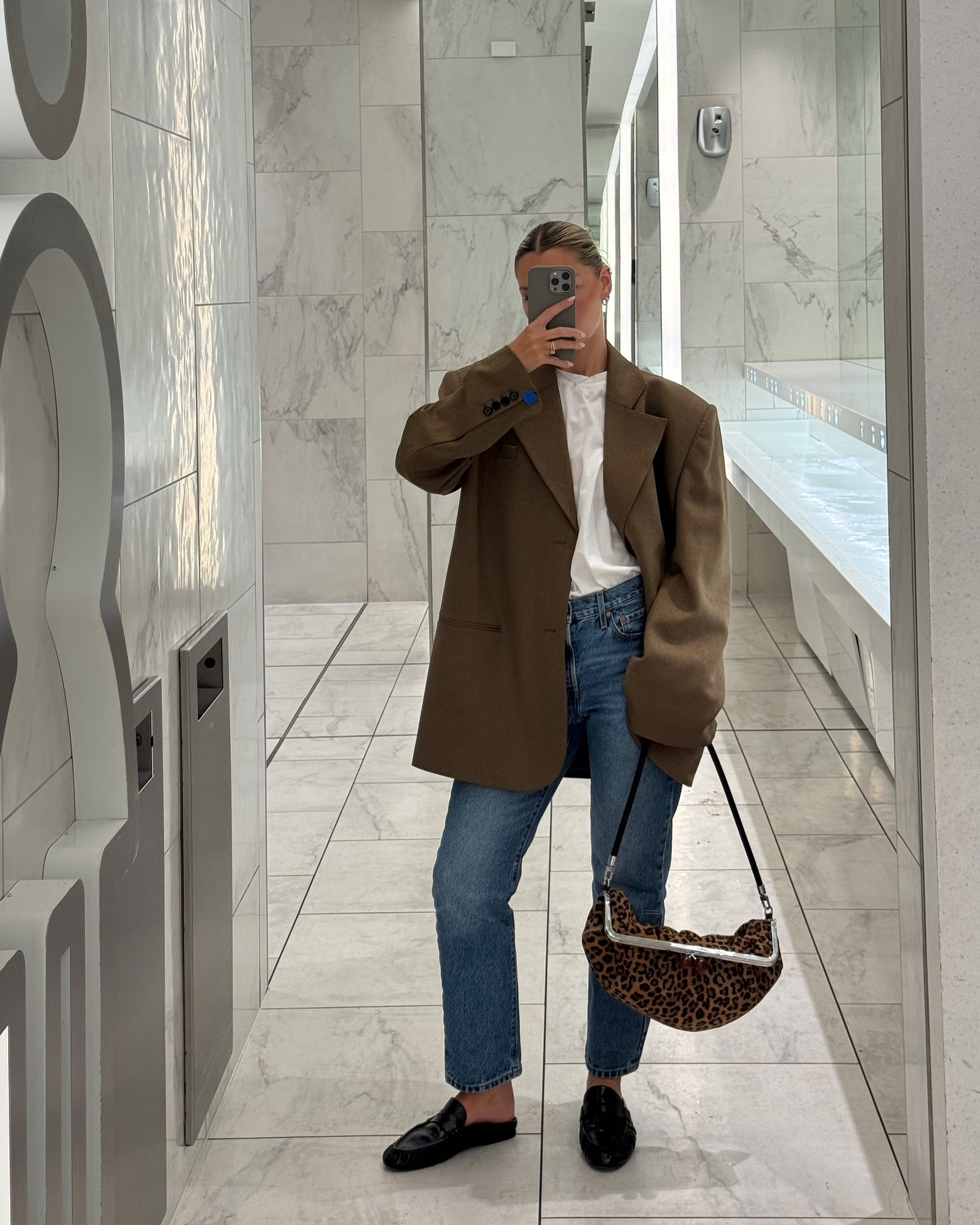 Fashion person Julia Sokele wears the best autumn jackets in blazer form. She pairs her blazer with a white t-shirt denim jeans and slip on loafers. She is taking a bathroom selfie in a recent image from her Instagram.