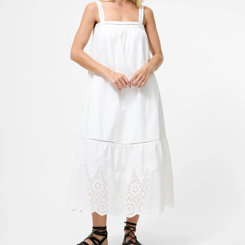 A model wearing a white lace dress and strappy sandals