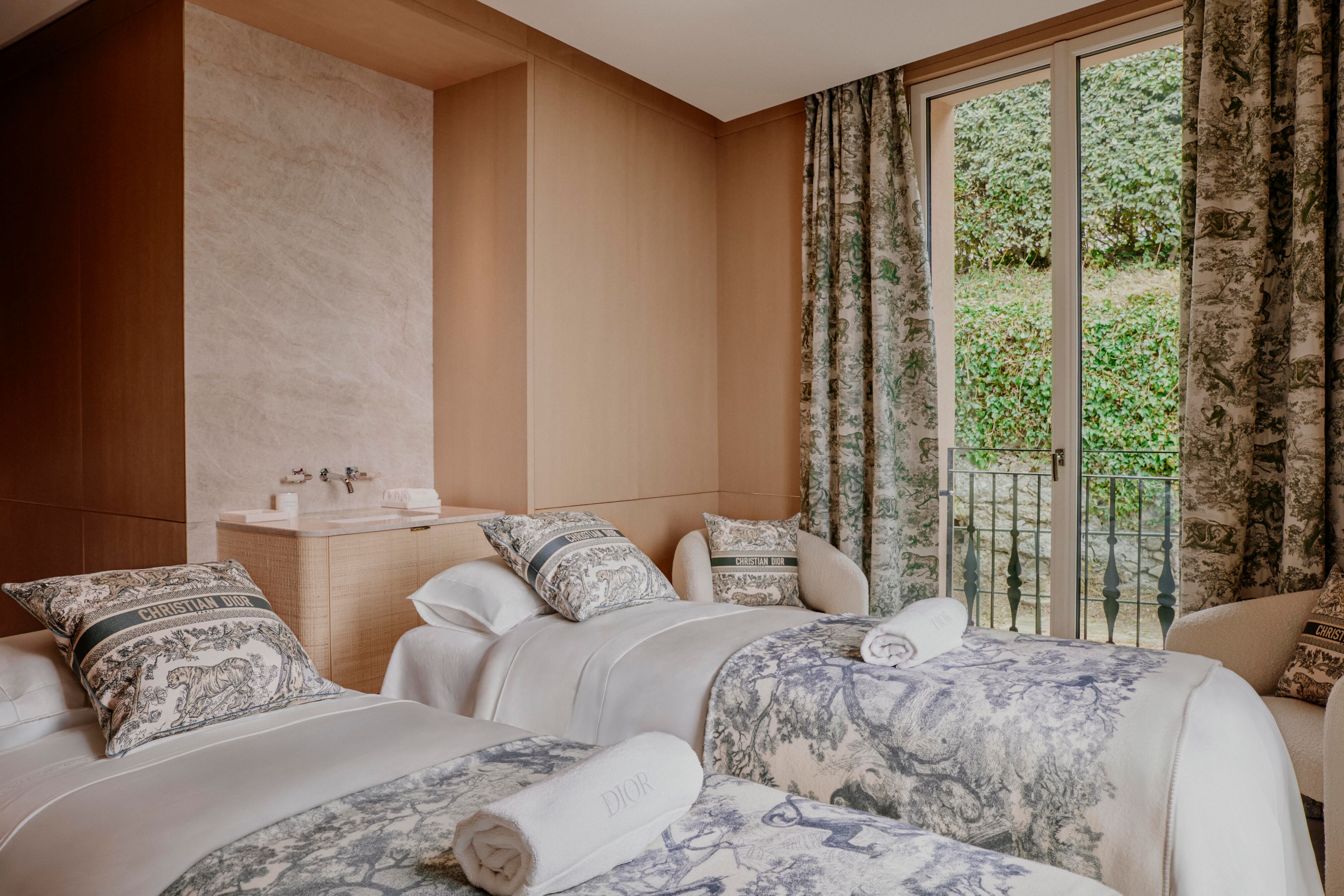 Two spa beds inside a pale wooden room, with windowed doors out into some greenery