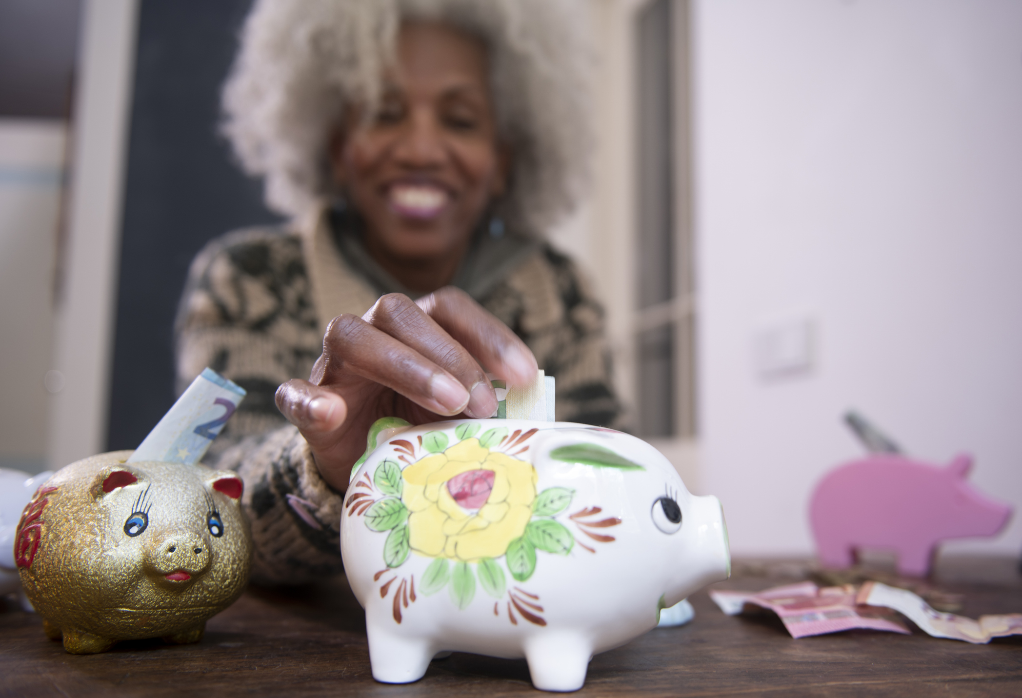 a woman depositing dollar bills into a flowery piggy bank