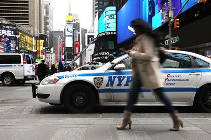 A woman walks in front of an NYPD vehicle.