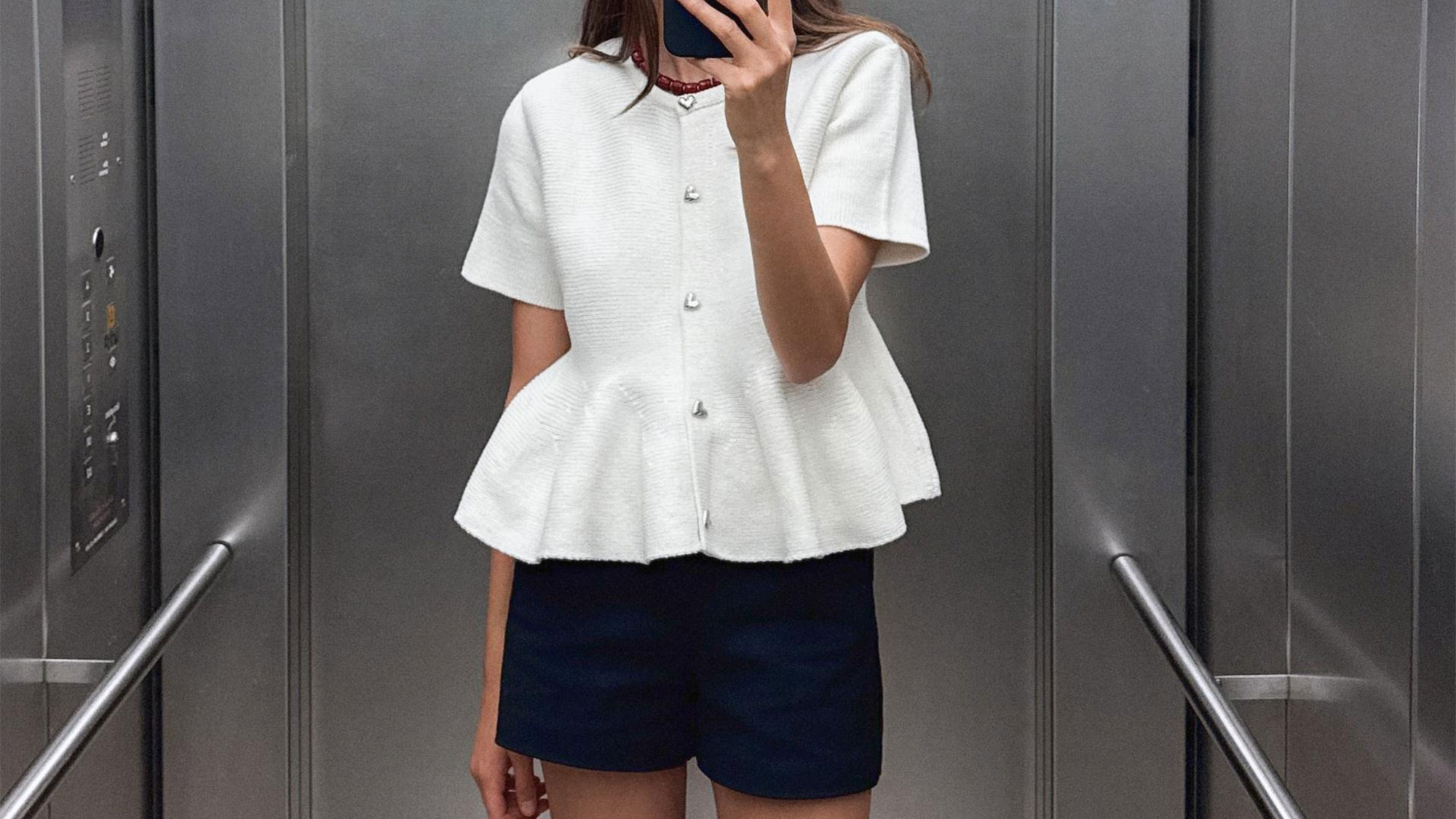 Woman wearing a white peplum blouse from Zara.