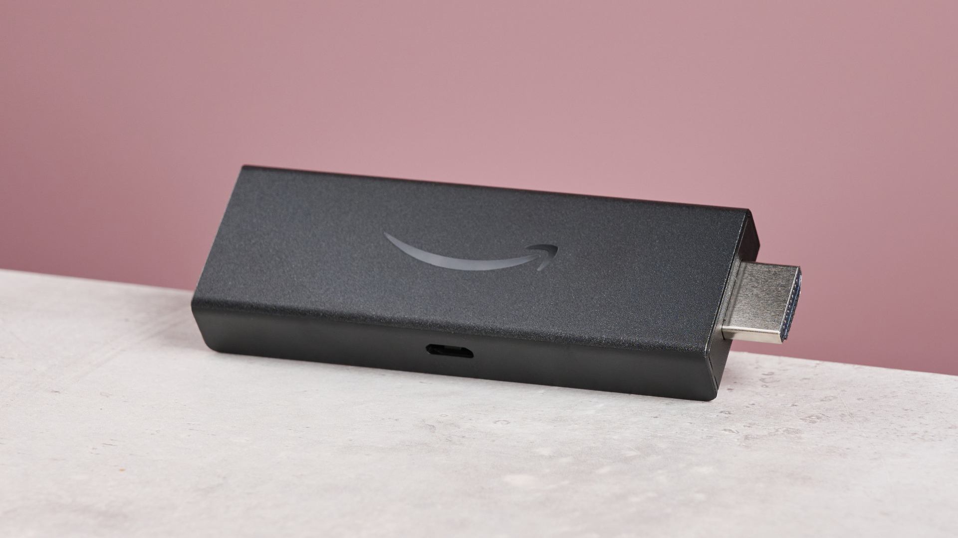 The Amazon Fire TV Stick HD lies on its side on a grey tabletop.