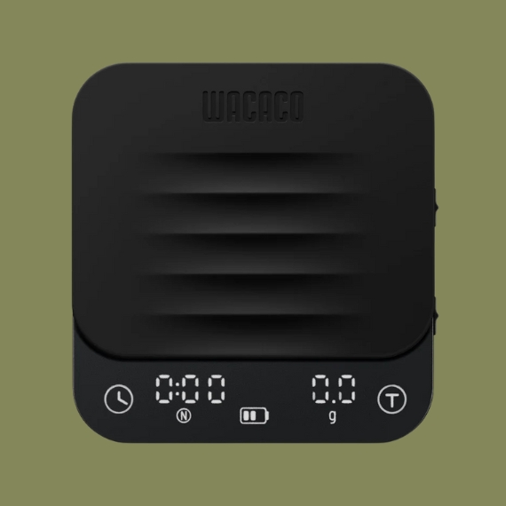 A black modern scale with a textural, gummy top reading "WACACO" sits against a dark green background.