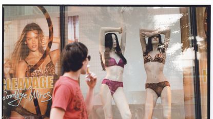 man looking at mannequins in lingerie in storefront window