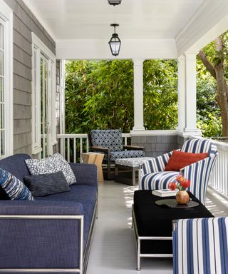 front porch with both armchairs and couch, lantern, blue and white scheme, coffee table, pillows, wooden side table
