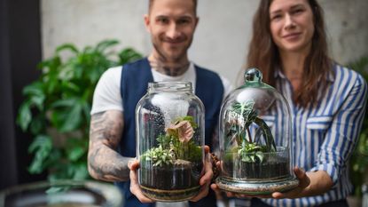 A smiling man and woman hold terrariums