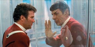 William Shatner as Captain Kirk looking through the glass at a dying Spock holding up live long and prosper hand sign in Star Trek: Wrath of Khan