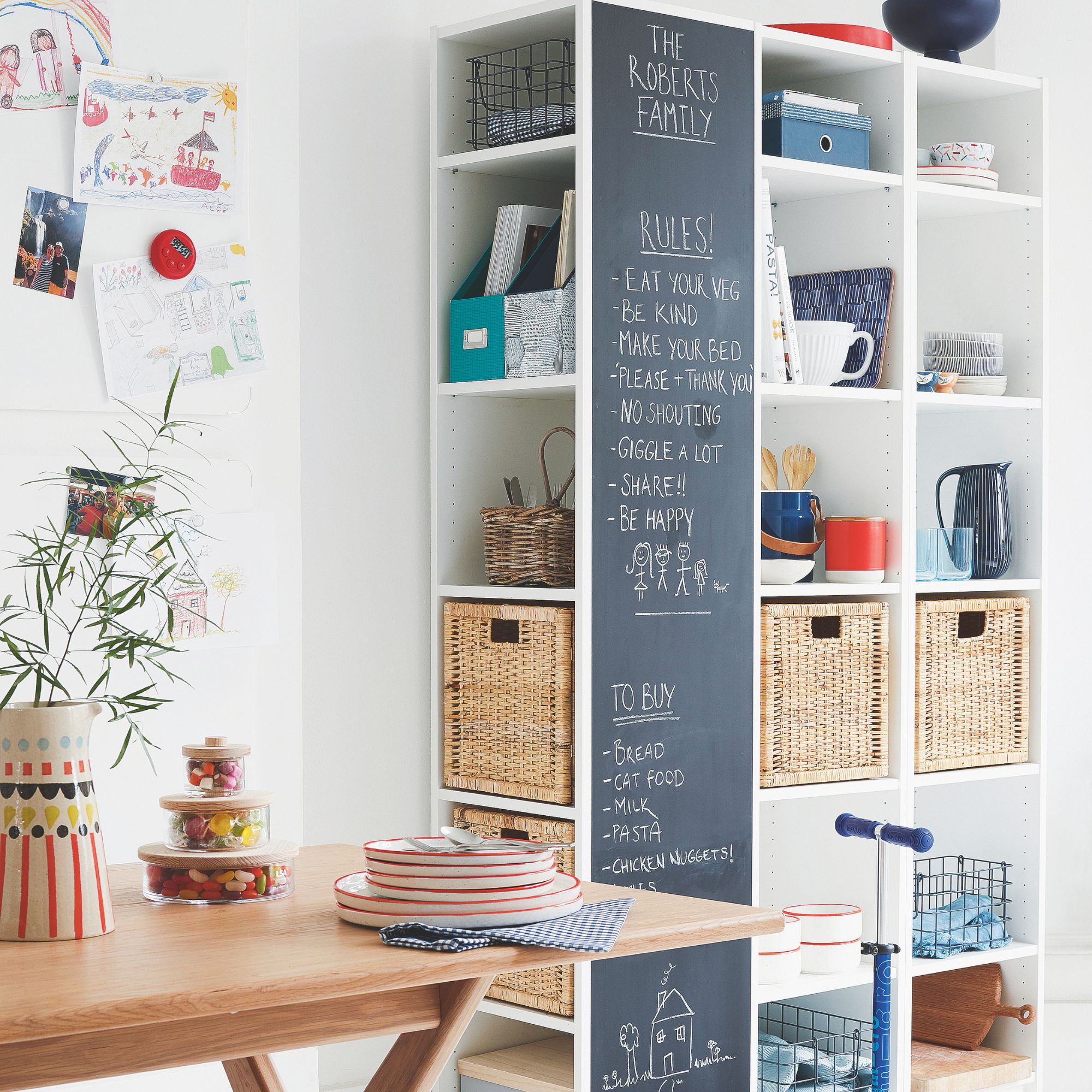 Dining room with wooden table and a storage unit that&#039;s filled with storage boxes and has a chalkboard on the front