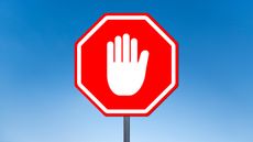 A white hand in the stop gesture on a red stop sign.