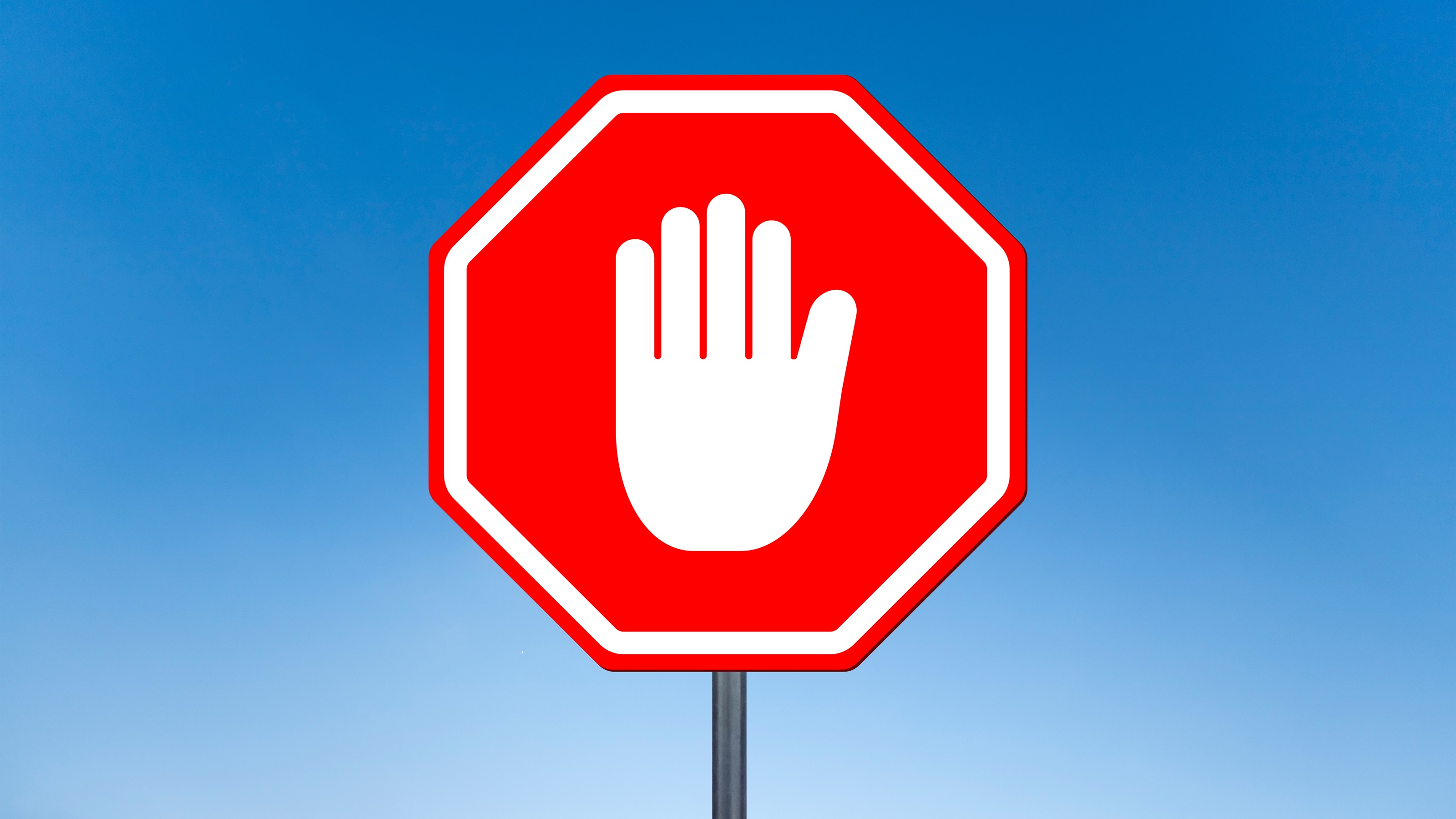 A white hand in the stop gesture on a red stop sign.