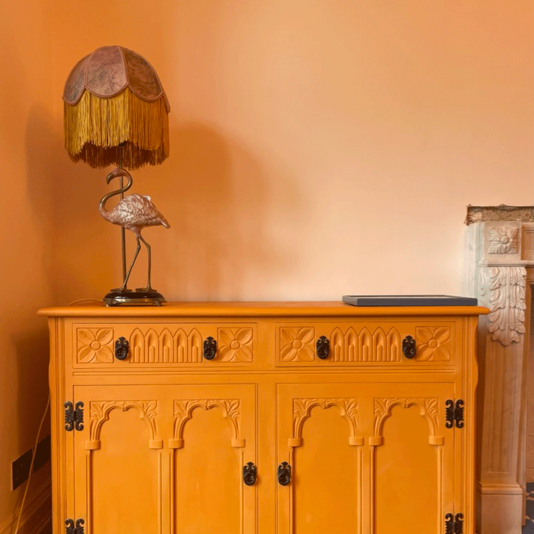 Yellow dresser with flamingo lamp sitting on top