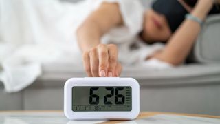 Woman snoozing her alarm clock