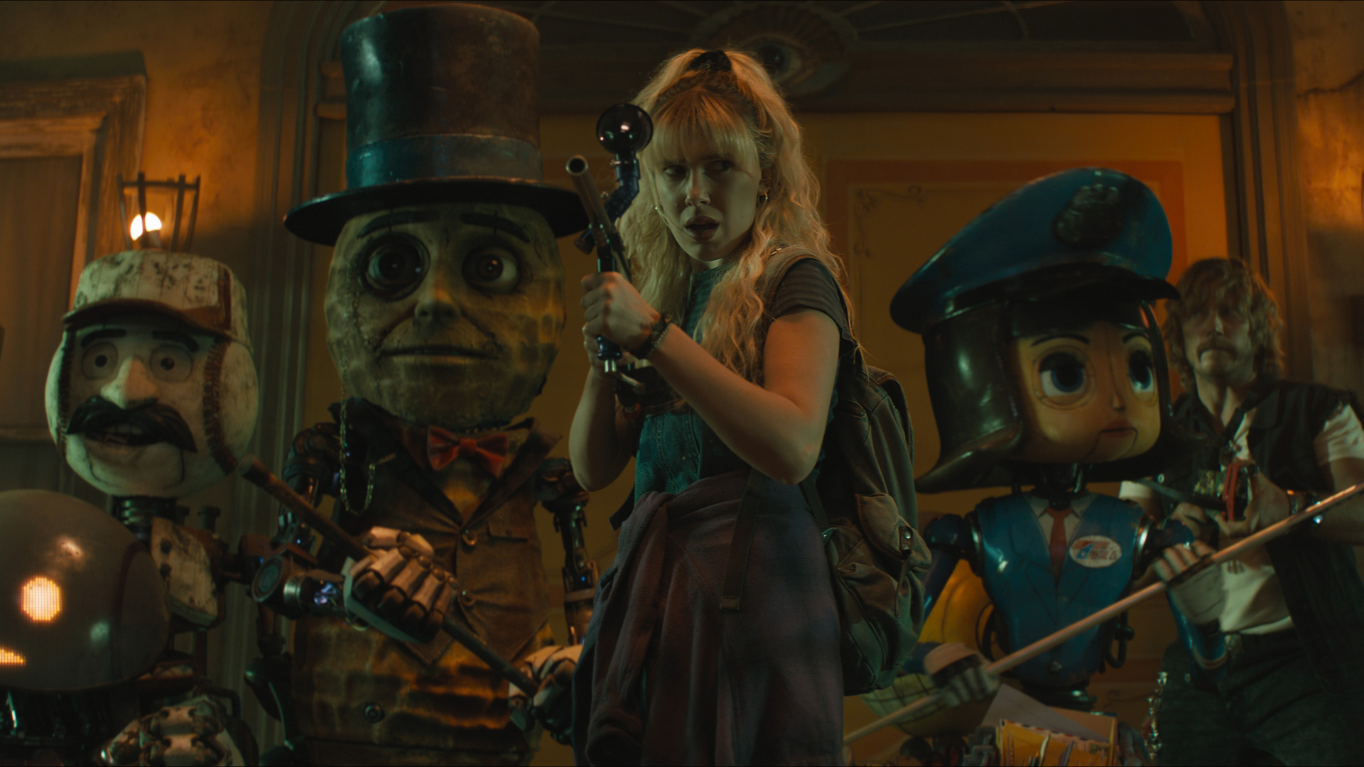 Michelle aims her gun as she stands next to some robot mascots in The Electric State film